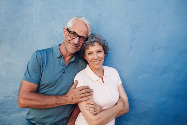 Couple smiling and standing in front of blue wall.