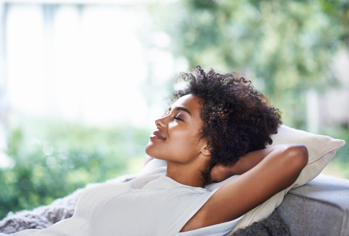 Woman laying back on pillow with arms crossed behind head.