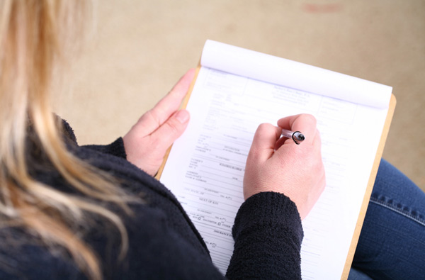 Woman filling out insurance paperwork, at Fusion Dental Specialists in Happy Valley, OR.