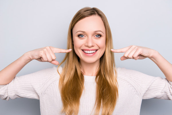 Smiling woman pointing at her healthy smile.