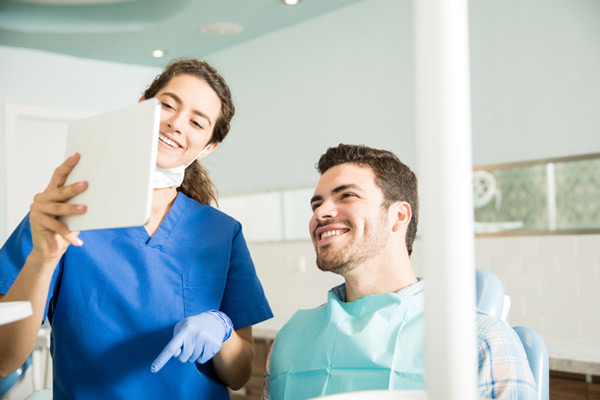Male patient in dental chair reviewing dental services with dentist