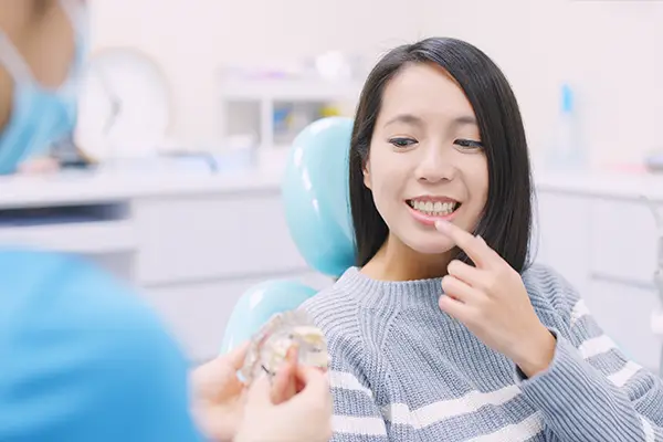 Doctor explaining the dental implant process to a patient while she reflects on her own dental health.