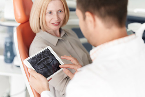 Older woman discussing dental implants with her dentist at Fusion Dental Specialists in Happy Valley, OR